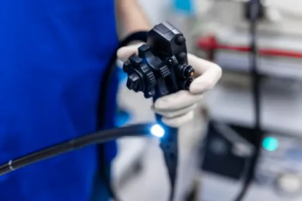 Doctor proctologist holding endoscope during colonoscopy.
