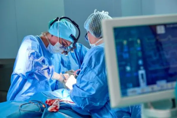 Electrocardiogram in hospital surgery operating emergency room showing patient heart rate with blur team of surgeons background