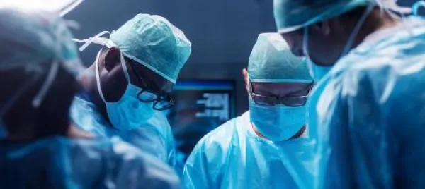 Diverse team of professional medical surgeons perform surgery in the operating room using high-tech equipment. 