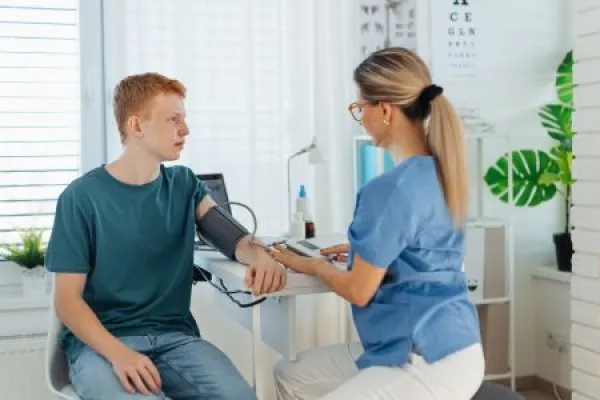 Doctor measuring boy's blood pressure, using blood pressure monitor.