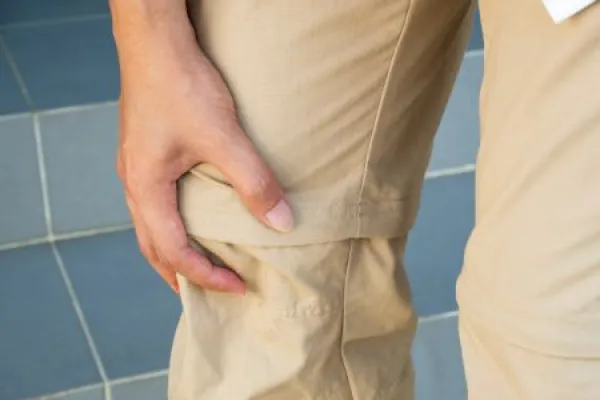 Close-up of painful right knee held by hand while descending home stairs