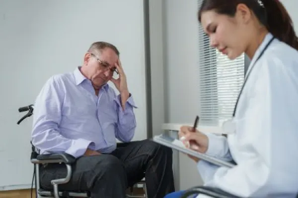 Doctor consulting patient in wheelchair about health issues 