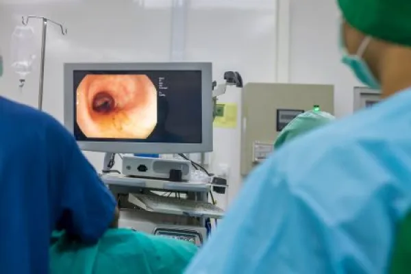 A doctor or surgeon in a light blue protective gown did a colonoscopy or gastroscopy inside operating theatre in the hospital.