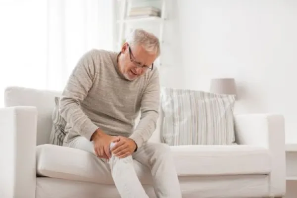 people, health care and problem concept - unhappy senior man suffering from knee ache at home