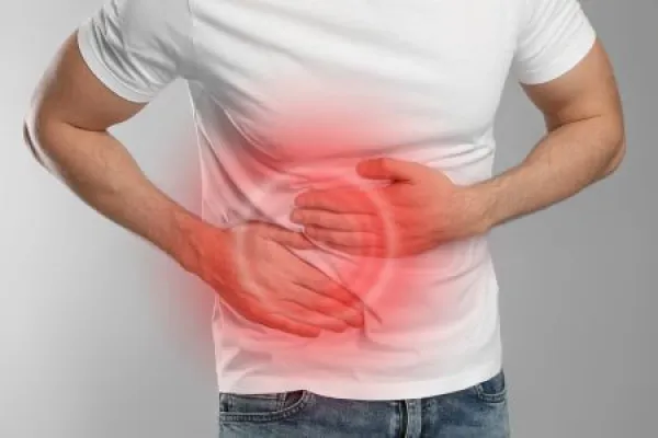 Man suffering from pain in lower right abdomen on light grey background, closeup.