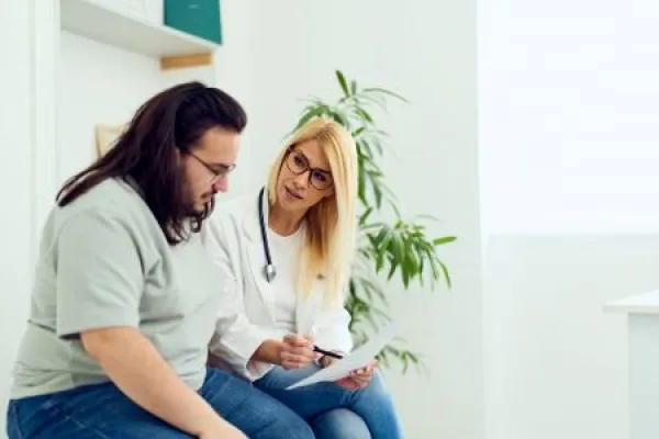 Doctor Counseling Overweight Patient During Medical Consultation In Clinic Office Showing Empathy And Support