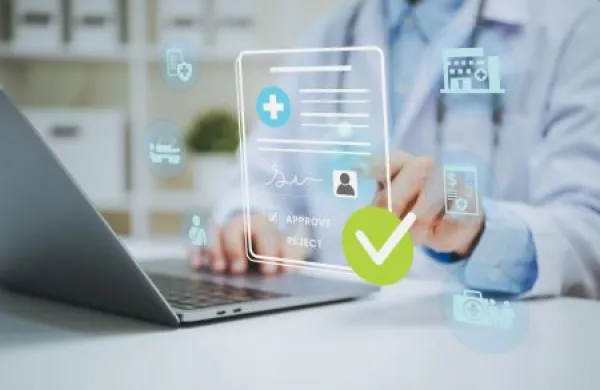 Doctor reviewing digital health insurance approval on laptop managing patient eligibility medical claims