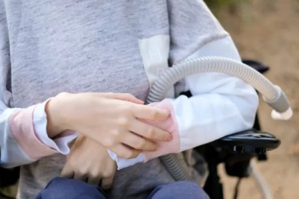 Hands of a disabled person with muscular dystrophy holding a ventilator for deep breathing, concept, background 