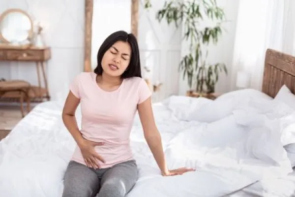 Chinese Girl Having Lower Abdominal Pain Sitting In Bed Indoors 