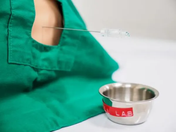 Downloaded Close-up detail of a physician collecting spinal fluid from a pediatric training dummy using a lumbar needle.