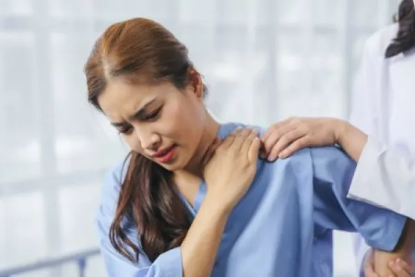Doctor comforting her patient suffering from shoulder pain, medical and healthcare concept