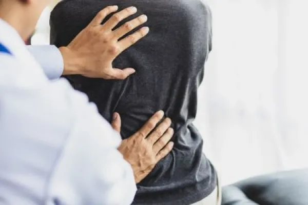Doctor examining woman back pain in examination room.