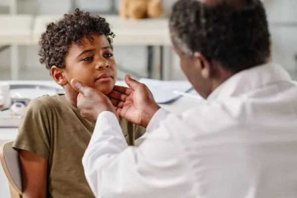African little boy visiting pediatrician at hospital, he complaining on his sore throat