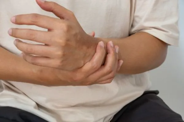 Asian man holding painful left wrist after morning routine.