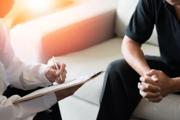 Doctor physician consulting with male patients in hospital exam room.